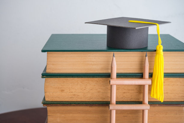 课本上的毕业帽和铅笔梯放在教室背景抄写处。图片下载