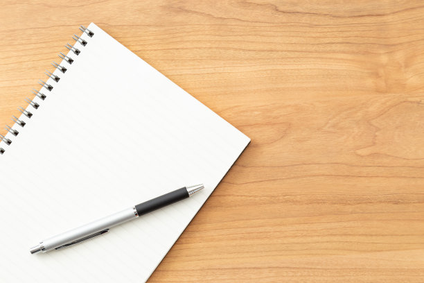 桌上有一个笔记本和一支笔。图片下载