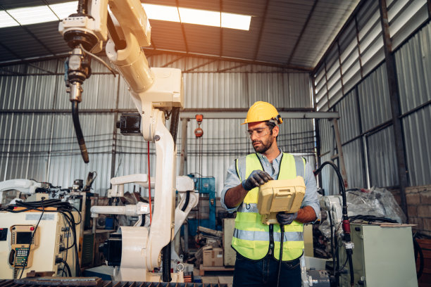工程师或工人正在控制机器臂焊接钢材。图片下载