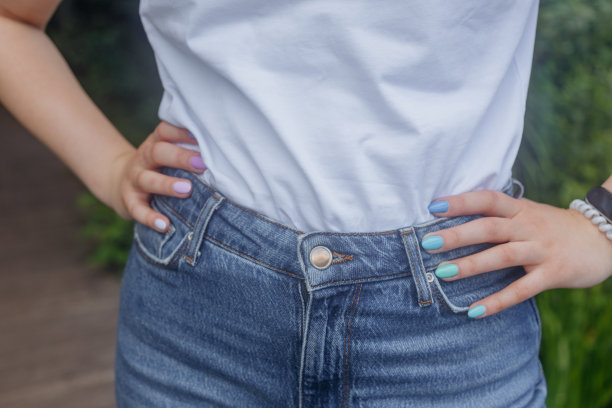 照片上，一个年轻女孩穿着白色t恤和牛仔裤，双手放在腰上，指甲上涂着五颜六色的指甲油。图片下载