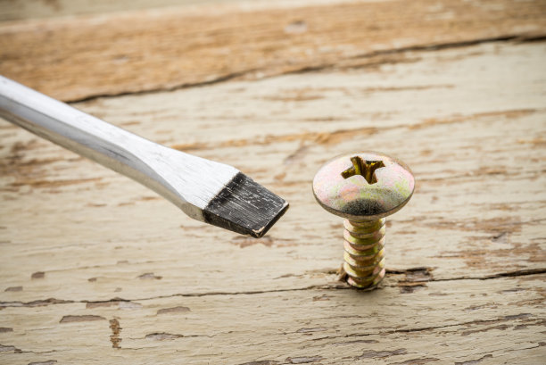 这个工具用错了。螺丝和螺丝刀在旧的木制背景。图片下载