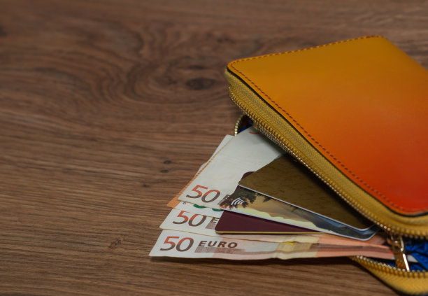 木桌上放着一个装有50欧元钞票和信用卡的钱包。图片下载