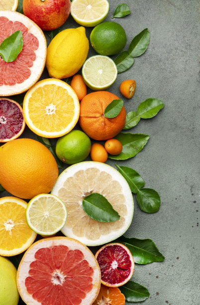 五颜六色的柑橘类水果，食物背景，俯视图。混合不同的整片水果:橙子，葡萄柚，柠檬，酸橙和其他带叶子的绿色石桌上图片下载