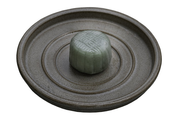 绿月饼以芋头、黑芝麻和金线蛋为馅料，装在陶瓷盘子上，在白色的背景上用剪子隔开。图片下载