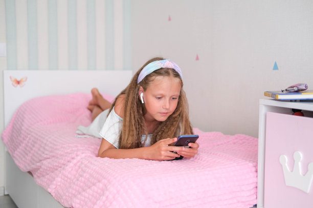 孩子玩手机，用无线耳机听音乐。图片下载