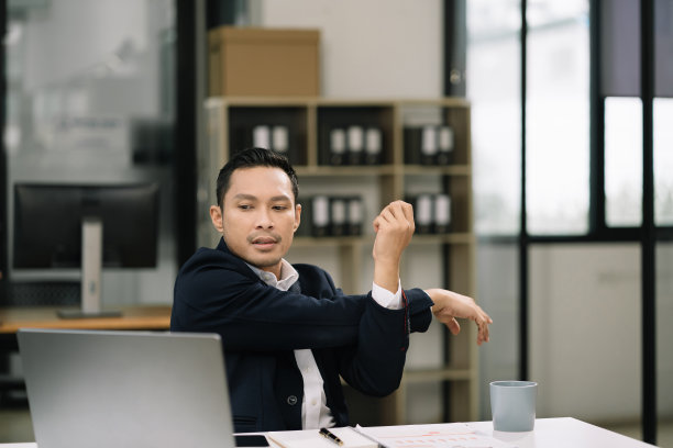 商人是由于在办公室坐得太久而做伸展姿势的，这是办公室综合症的概念。图片下载