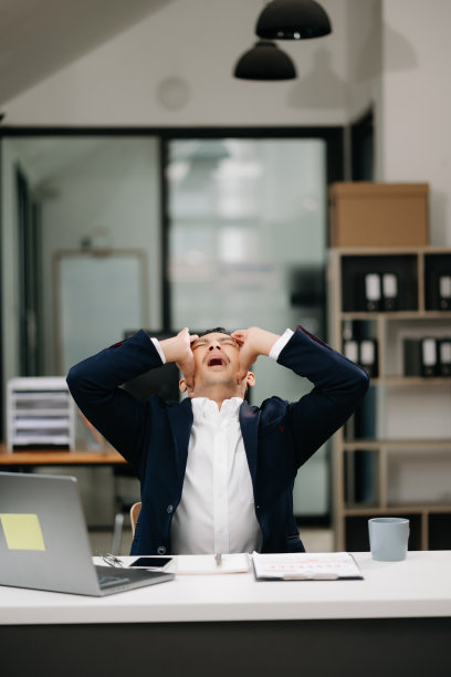 劳累过度的年轻亚洲商人办公室职员在办公桌前工作了一整天后颈部疼痛。办公室综合症概念图片下载