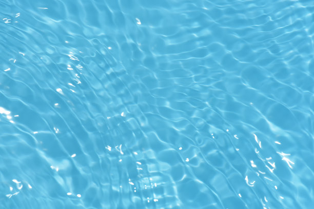 蓝蓝的水面上泛起涟漪。散焦模糊透明蓝色透明平静水面纹理与飞溅和气泡。水波与闪亮的图案纹理背景。图片下载