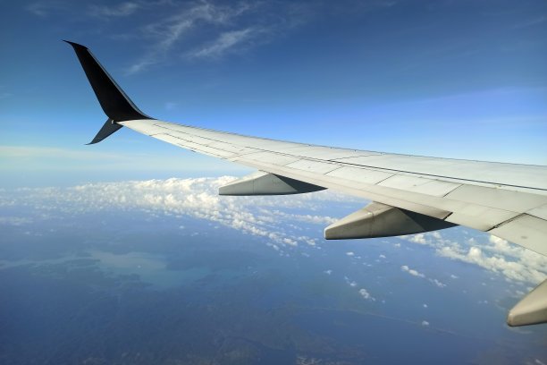 透过飞机窗户看到的商业喷气式飞机机翼在天空中飞行。航空旅行概念图片下载