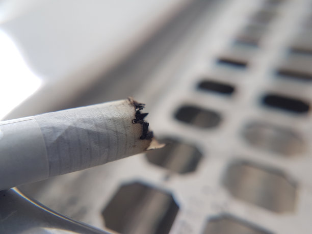 靠近一只放在不锈钢烟灰缸上的香烟图片下载