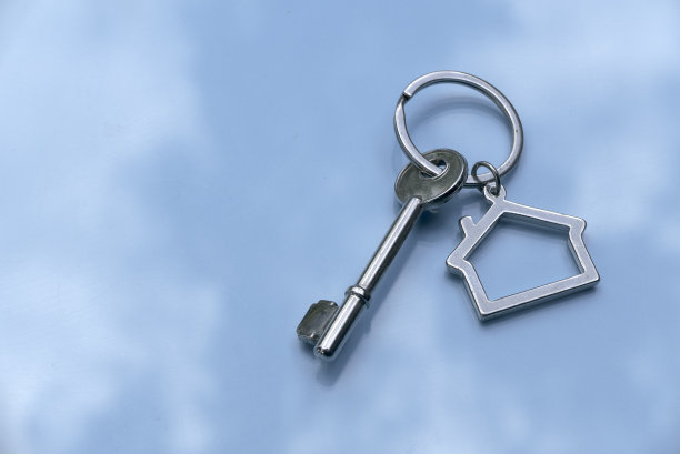 财产或不动产的概念。蓝色多云背景的房子钥匙。图片下载