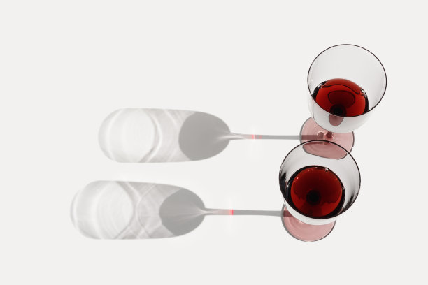 静物用彩色玻璃杯中干红的酒伴着阳光的阴影，盛夏平卧。两只酒杯，白底酒饮，复制空间，潮流审美图片下载