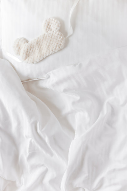 睡罩从枕头上的浅色毛皮在床上白色的被褥。静物细节，舒适的生活风格的家庭照片。蓬松的眼罩是最好的睡眠。家居舒适、安乐、睡眠的理念图片下载