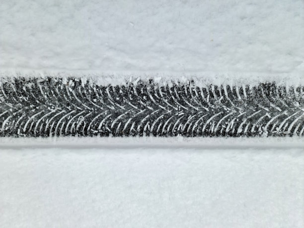 近距离观察积雪覆盖的街道上的轮胎痕迹。图片下载