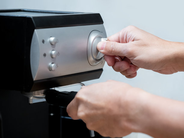 男咖啡师手握咖啡壶旋转旋钮在工作台上的咖啡机。图片下载