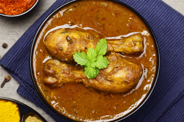 用薄荷叶装饰的碗里的马萨拉咖喱鸡图片下载