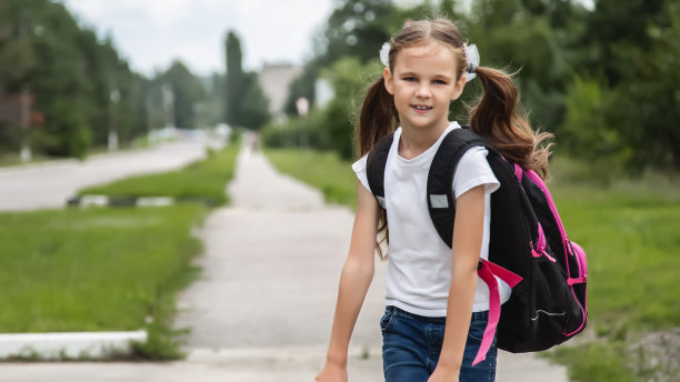 快乐的漂亮女学生背着书包。学生去上学，享受学习。学校、教育理念图片下载
