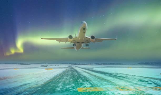 商用白色飞机飞越起飞跑道(冰)覆盖的机场与北极光-挪威图片下载