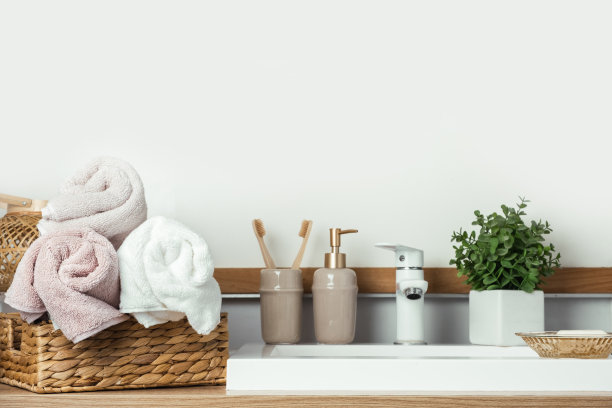 时尚的现代家庭浴室内部。白色的脸盆和带绿色植物的水龙头，干净的毛巾和沐浴用品图片下载