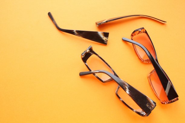 旧的破损眼镜和破损的眼镜腿，橙色的背景。视力不佳。重用和修复概念。健康的概念。光学眼镜失灵。视力矫正眼镜破损。近距离，平躺图片下载