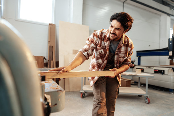 年轻的木匠在家具厂操作木工机器图片下载