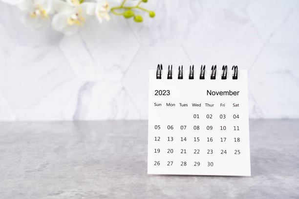 2023年11月的日历桌和大理石背景上的白色兰花。图片下载