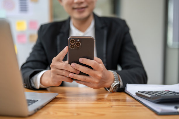 一个快乐的商人在办公桌前使用智能手机的特写照片图片下载