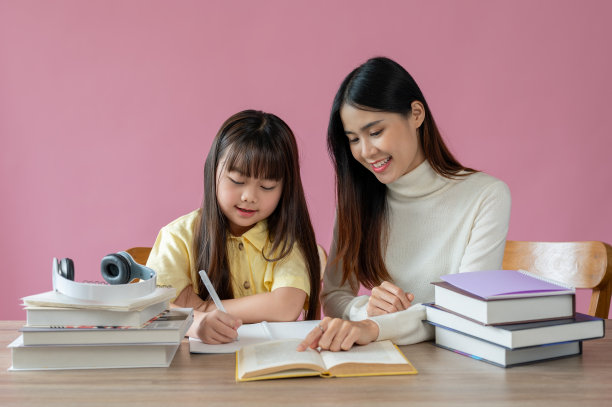 一位充满爱心和善良的亚洲私人教师正在教并帮助一个小女孩做家庭作业图片下载