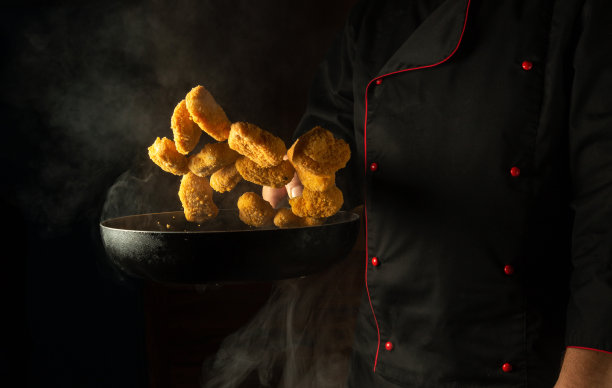 做酥脆的鸡块。厨师把热土豆扔进锅里。一个带有广告空间的酒店大厨房的概念图片下载