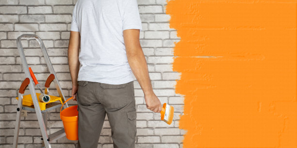 人们通过粉刷墙壁来翻新他们的房子。有文字位置的横幅。图片下载