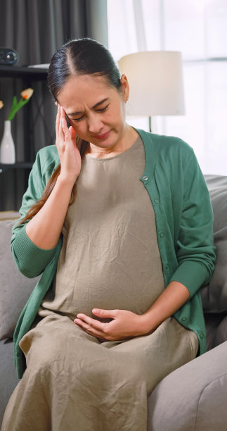 亚洲孕妇躺在家里的沙发上休息时感到恶心和头痛。图片下载