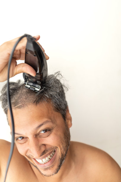 英俊的白发男子正在自己理发。图片下载