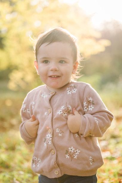 小女孩走在秋叶林中。孩子在公园里玩耍。一家人带着孩子一起在日落时分度假。秋天的假期在大自然。特写镜头。阳光下的春天心情照片图片下载