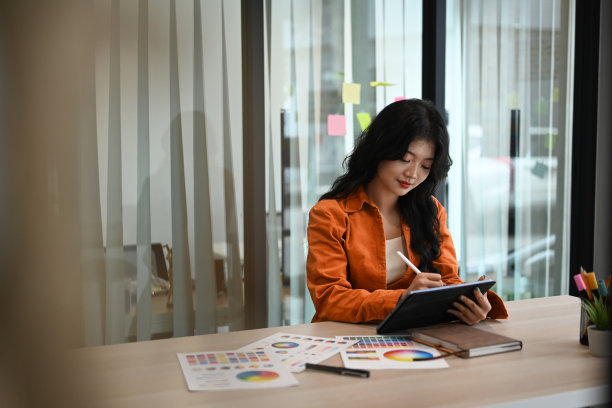 漂亮的年轻创意女性使用数字平板电脑，在现代工作场所使用调色板进行设计项目图片下载
