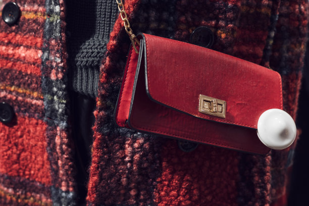 一个身穿红色格纹大衣的人体模特身上挂着一个金色链条上的红色女性手包。特写照片。软的焦点。图片下载