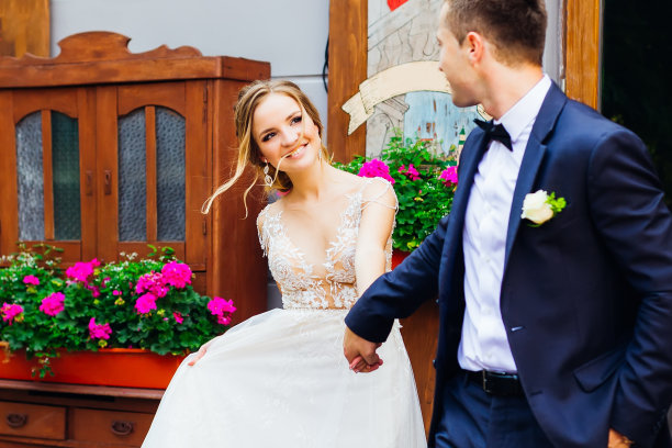 新娘牵着未婚夫的手，站在摆满花盆的老式衣橱旁图片下载