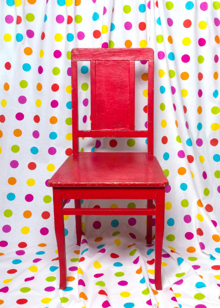 红色的旧椅子，映衬着色彩斑斓的圆点窗帘。图片下载