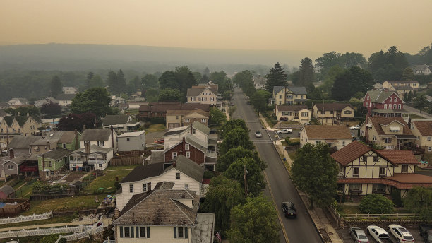 火灾烟雾中的住宅城镇景观。宾夕法尼亚州波科诺斯阿巴拉契亚山脉吉姆索普街道上的黄色天空笼罩着阴霾。鸟瞰图图片下载