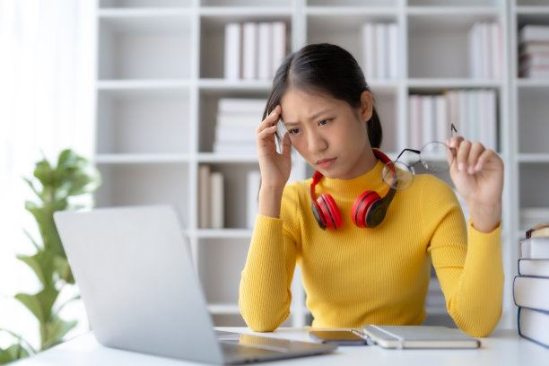 准备考试的亚洲女学生在图书馆看书时感到筋疲力尽。图片下载