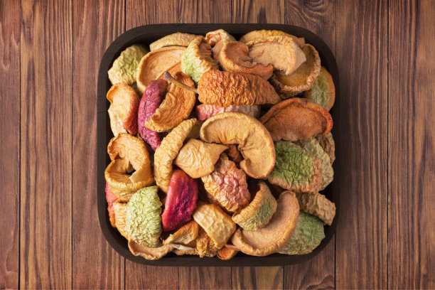 木桌背景上方形盘子里的干苹果。素食有机食品，健康饮食。图片下载