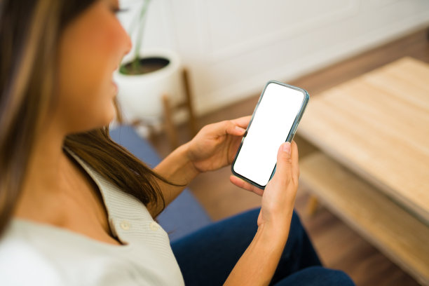 一个女人看着她的智能手机的空白屏幕的后视图图片下载