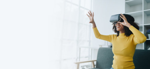 积极的非裔美国少女戴着未来VR头盔笑着放松。年轻的女孩对高科技视频游戏和虚拟现实小玩意很感兴趣，比如人工智能图片下载