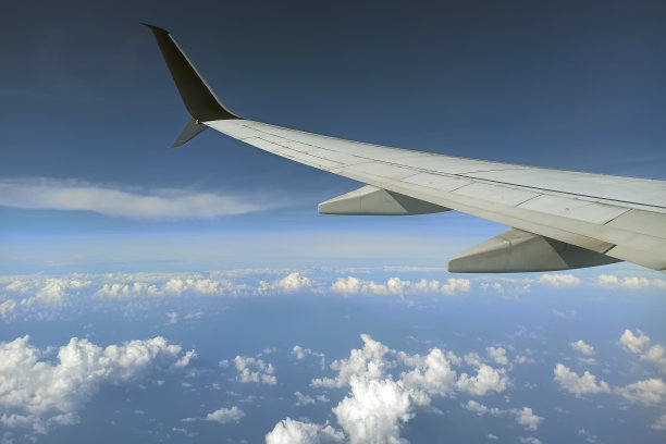透过飞机窗户看到的商业喷气式飞机机翼在天空中飞行。航空旅行概念图片下载