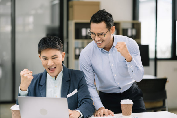 成功的商人团队，兴奋的年轻人保持积极的情绪，快乐地在现代办公室的电脑上工作图片下载