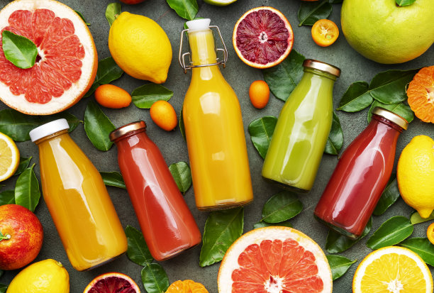 夏季水果饮料。瓶装柑橘汁和冰沙，食物背景，俯视图。混合不同的水果:橙子，葡萄柚，酸橙，带叶子的橘子和饮料放在绿色的桌子上图片下载