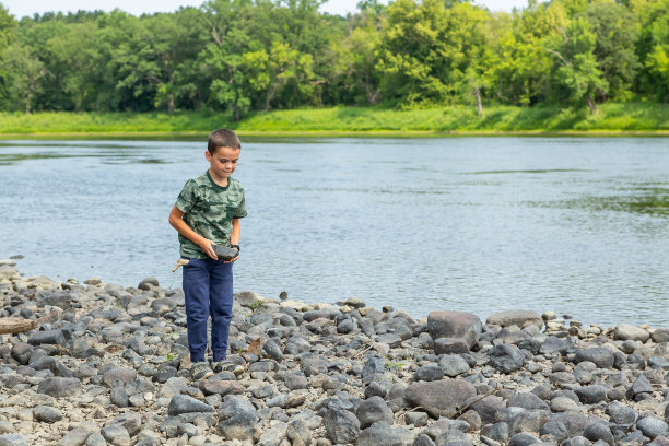 男孩抱着岩石探索密西西比河河床图片下载