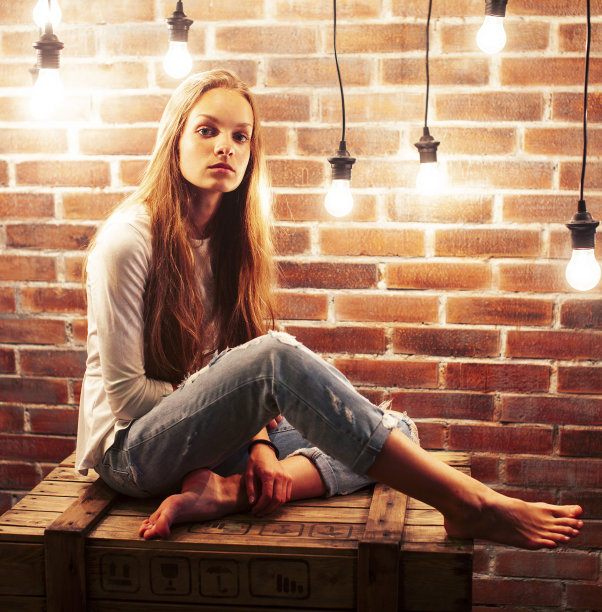 年轻的十几岁的女孩摆出欢快的姿势在现代阁楼工作室室内与许多灯，生活方式度假的人的概念图片下载