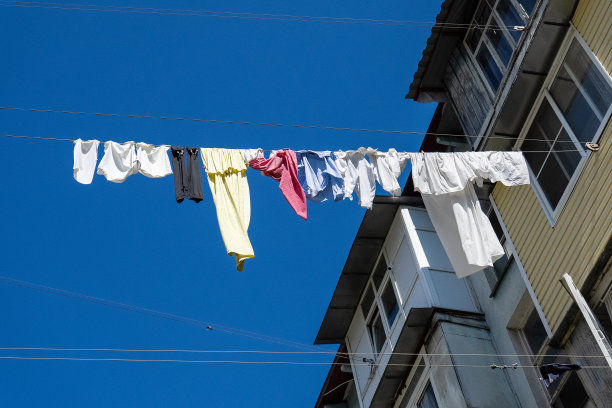 在老房子外面晾晒洗过的衣服。洗过的衣服晾晒。新鲜干净的衣服正在外面晒干。图片下载