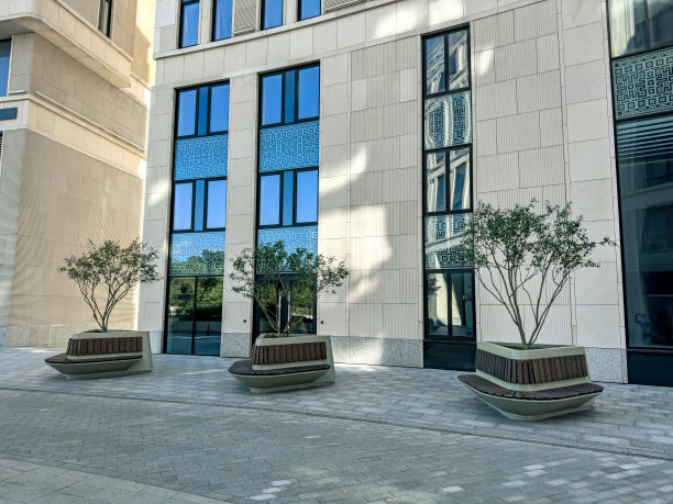 在现代办公大楼的院子里，有大盆栽树和长椅。图片下载