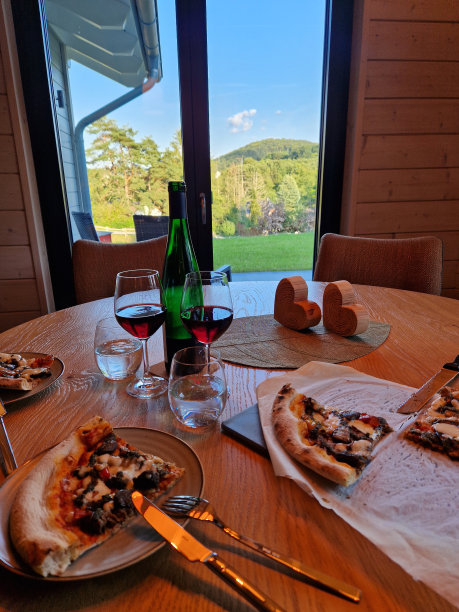 在德国艾菲尔的丘陵景观前，吃着披萨和红酒的餐桌图片下载